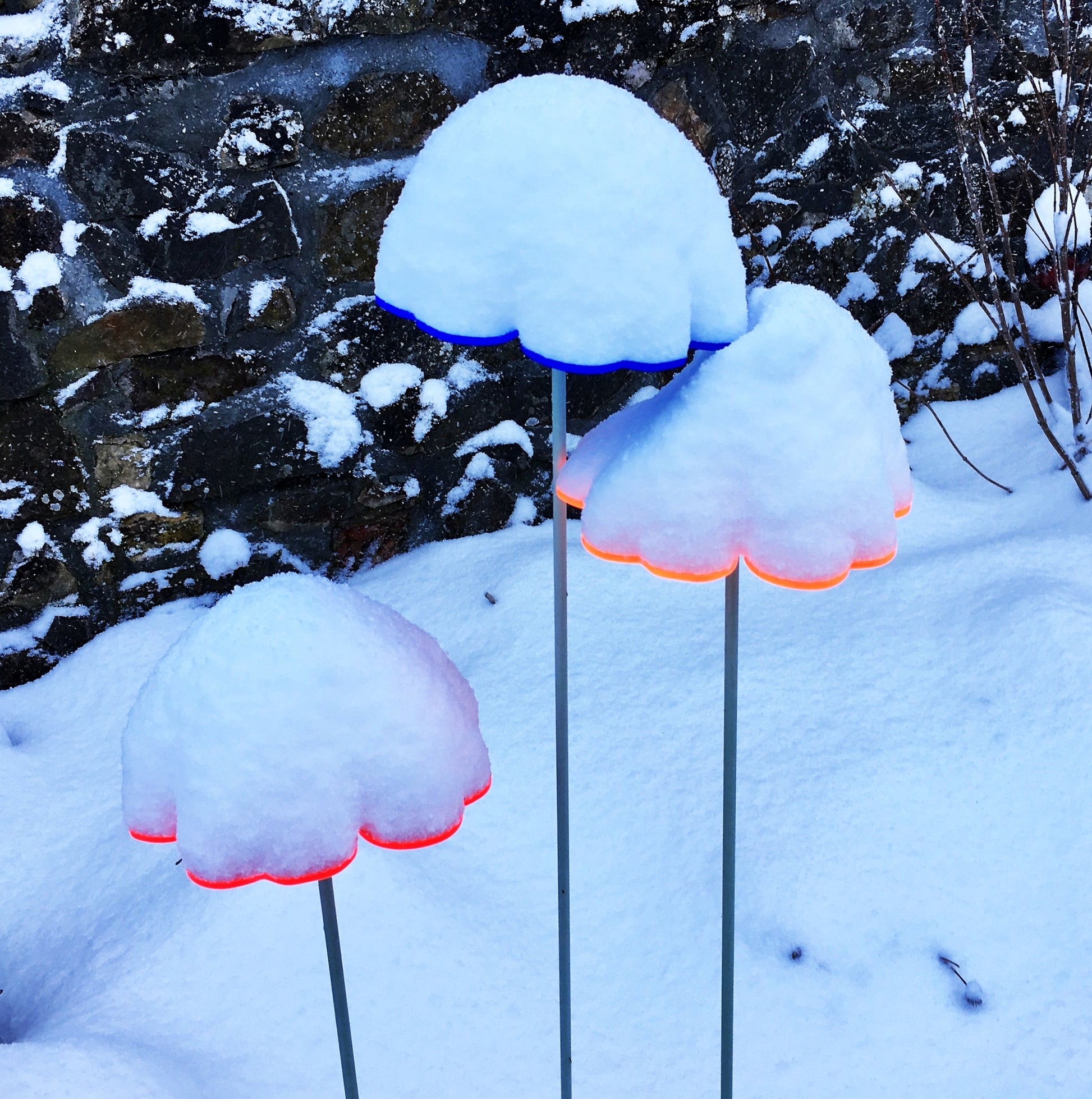 Set of 3 Large Double Blossoms Garden Decor Stake in three colours red, orange and blue. This image shows the Double Blossoms covered in snow and still glowing at the edges.